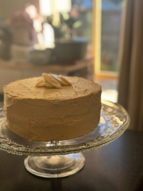 A freshly baked, premium gluten-free banana cake featuring a natural yellow hue from organic fruit powder, presented on a white plate.