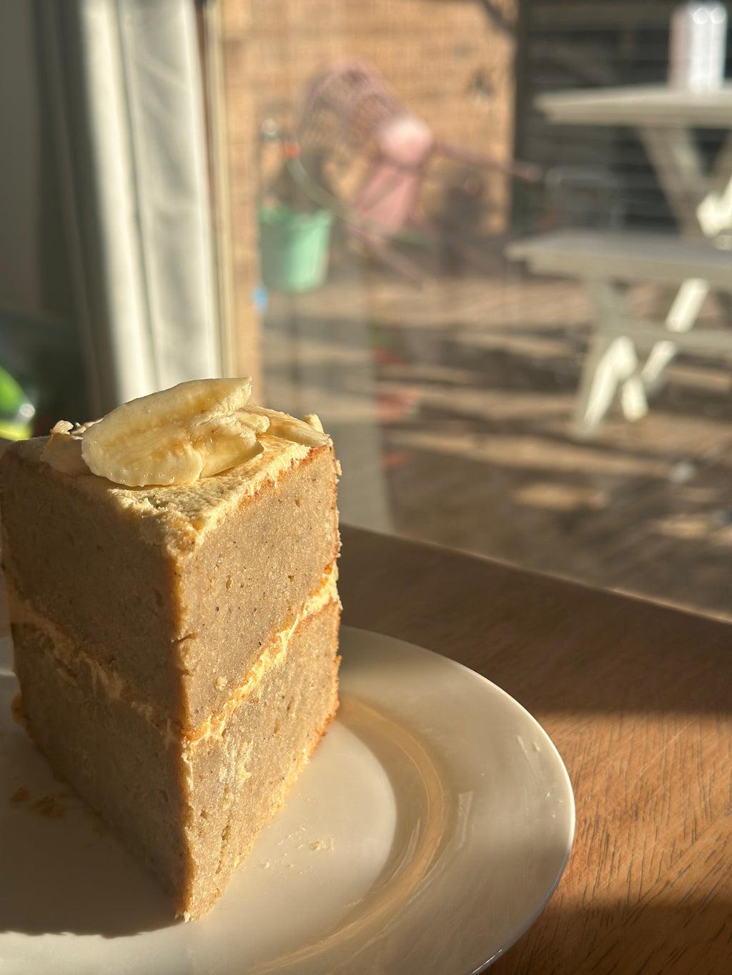 A freshly baked slice of, premium gluten-free banana cake featuring a natural pink hue from organic fruit powder, presented on a white plate.
