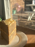 A freshly baked slice of, premium gluten-free banana cake featuring a natural pink hue from organic fruit powder, presented on a white plate.