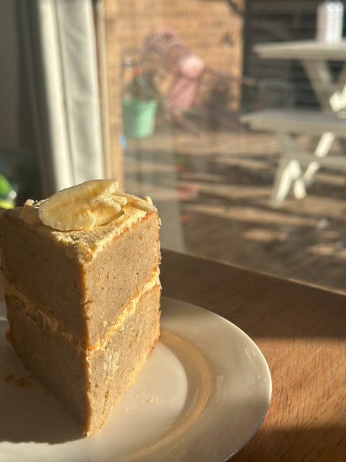 A freshly baked slice of, premium gluten-free banana cake featuring a natural pink hue from organic fruit powder, presented on a white plate.